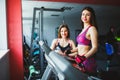 Woman with personal trainer exercising on treadmill in gym