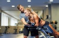 Woman with personal trainer flexing muscles in gym Royalty Free Stock Photo