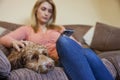 Woman With Pet Cockapoo Dog Relaxing On Sofa Checking Mobile Phone At Home Royalty Free Stock Photo