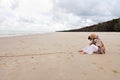 Woman and pet dog sitting on beautiful deserted beach Royalty Free Stock Photo