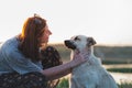 Woman pets dog in the nature at sunset.