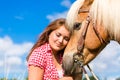 Woman petting horse on pony farm