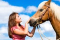 Woman petting horse on pony farm