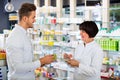 Woman pharmacist helping customers in drug store