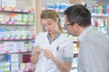 woman pharmacist helping customers in drug store