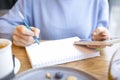 A woman with a phone in her hands sits at breakfast and works, writes in a notebook. Royalty Free Stock Photo