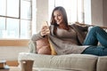 Woman, phone and relax on sofa for social media, app and text in her home, happy and smile. Girl, smartphone and app for