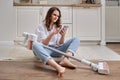 A woman with a phone sets up a wireless portable vacuum cleaner sitt Royalty Free Stock Photo