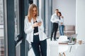 Woman with phone standing in front of group of young successful team that working and communicating together indoors in Royalty Free Stock Photo