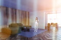 Woman with phone in wooden and white room with green sofa and dining room Royalty Free Stock Photo