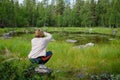 Woman photograph meteor crater lake Finland in green coniferous forest