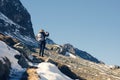 A woman photographer with camera and backpack in a winter jacket with fur stands on the snow mountain in Switzerland. Fluela pass