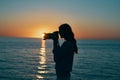 woman photographer with camera at sunset near the sea on the beach Royalty Free Stock Photo