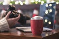 Woman photographer checking photos looking at camera near laptop with cup of hot chocolate and marshmallow at christmas time Royalty Free Stock Photo