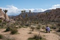 Woman photographer kneels to take photos of a cholla cactus in Joshua Tree National Park, wearing casual clothing Royalty Free Stock Photo