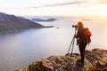 Woman photographer photographing fjord in Norway with DSLR and tripod Royalty Free Stock Photo