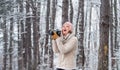 Woman photographer with professional camera. Winter hobby. Enjoy enchanting paleness and freezing atmosphere of winter