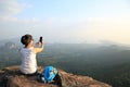 Woman photographer taking photos at mountain peak Royalty Free Stock Photo