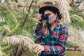 Woman photographer taking photos using camera in summer garden wearing coronavirus mask. Freelancer working in park Royalty Free Stock Photo