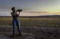 Woman photographer taking pictures of a golden field at sunset Royalty Free Stock Photo