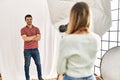 Woman photographer talking pictures of man posing as model at photography studio happy face smiling with crossed arms looking at Royalty Free Stock Photo