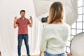 Woman photographer talking pictures of man posing as model at photography studio relax and smiling with eyes closed doing