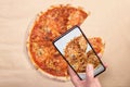 Woman photographing delicious pizza with mobile phone, smartphone to post to social networks, messenger