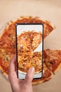 Woman photographing delicious pizza with mobile phone, smartphone to post to social networks, messenger. Vertical Orientation