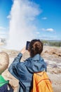 Woman photographing eruption of Strokkur Geyser in Iceland