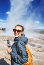 Woman photographing eruption of Strokkur Geyser in Iceland