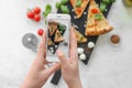 Woman photographing slices of delicious pizza Margherita with mobile phone