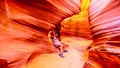 Woman photographing the smooth curved Red Navajo Sandstone walls of Rattlesnake Canyon