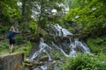 Woman Photographing Waterfall in Lush Forest by the Old Water Mill Royalty Free Stock Photo