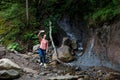 Woman photographs herself against the background of a waterfall