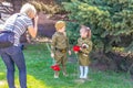 A woman photographs two children in military uniform during the action