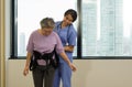 Woman physical therapist in blue uniform help an elderly to exercise and practice walking with Safety Transfer Belt. Atmosphere in