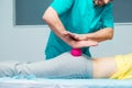 Woman at the physiotherapy receiving ball massage from therapist. A chiropractor treats patient`s femur buttock in medical office