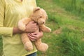 The woman picked up a little teddy bear, which was given on a birthday, to stroll in the park in order to play with his friends