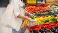 Woman picking bell peppers in a reusable bag. Ecology, Earth Day thematics