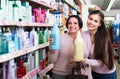 Woman picking bottles with shampoo and conditioner from shelf in