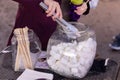 A woman picking marshmallows from a big glass jar using long tongs