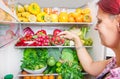 Woman picking some fruit on full fridge