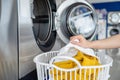 Woman picking up dirty clothes in a bin and putting them in the washing machine in a laundry shop Royalty Free Stock Photo