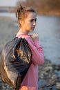 Woman picking up trash and plastics cleaning the beach with a garbage bag. Environmental volunteer activist against climate change Royalty Free Stock Photo