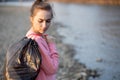 Woman picking up trash and plastics cleaning the beach with a garbage bag. Environmental volunteer activist against climate change Royalty Free Stock Photo