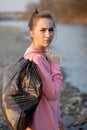 Woman picking up trash and plastics cleaning the beach with a garbage bag. Environmental volunteer activist against Royalty Free Stock Photo