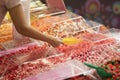 Woman picks colorful candies, sweets, puts them into paper package in candy shop.