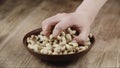 Woman Picks Up A handful Cashew, To Eat, From Her Bowl. took a nut on the right side