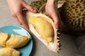 Woman with piece of fresh durian at grey table, top view