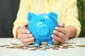 Woman with piggy bank and coins at light table Royalty Free Stock Photo